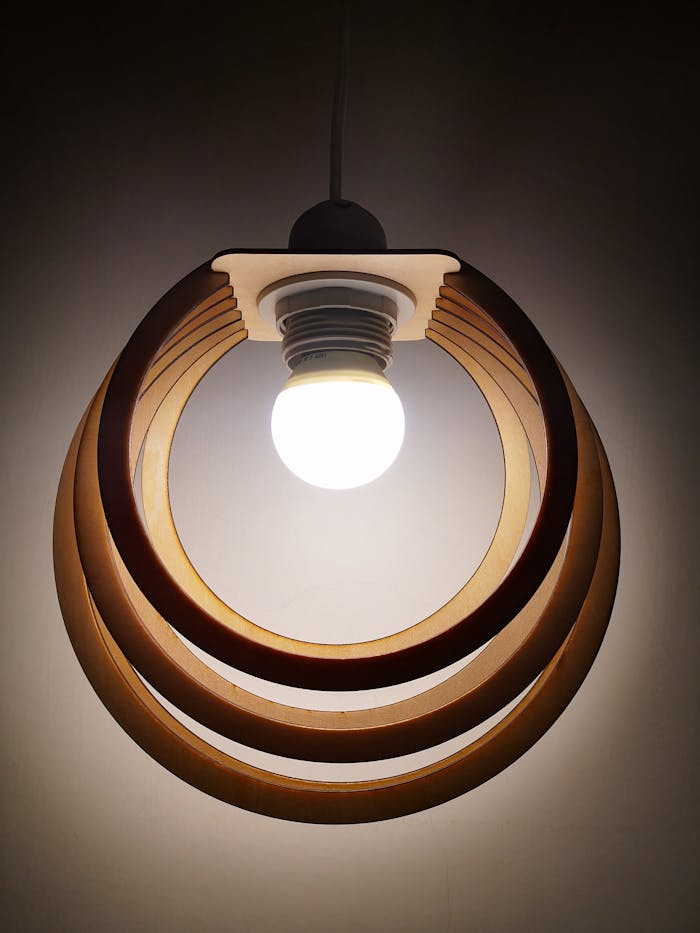 Elegant wooden pendant light fixture featuring concentric rings and a glowing bulb.